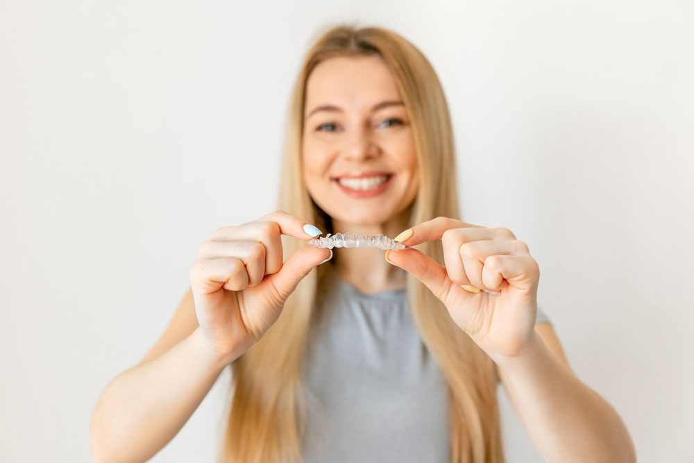 Woman holding clear aligners for Invisalign treatment in Los Angeles
