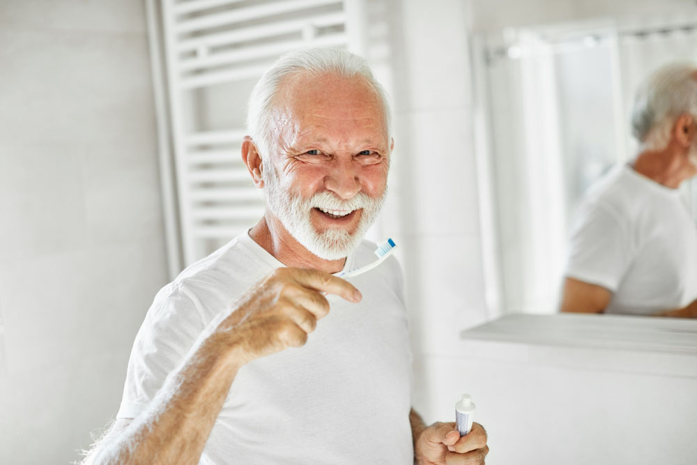 man brushing teeth to maintain healthy oral hygiene and a bright smile
