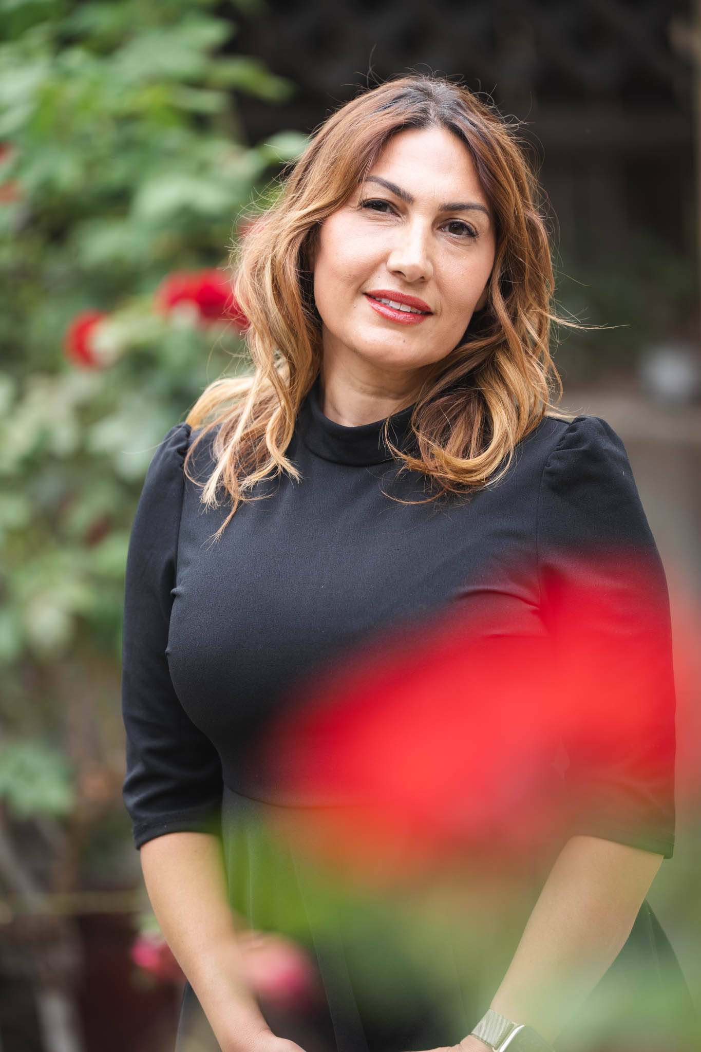 A Briter Smile team member in a black top standing among red flowers