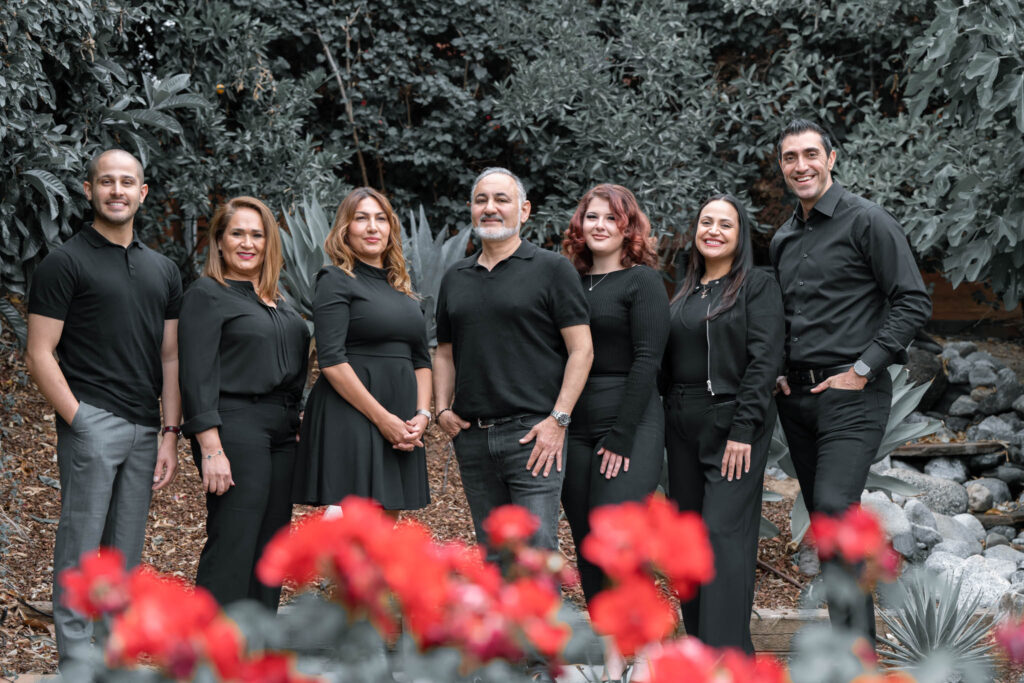 The A Briter Smile Dental Group team standing together outside among red flowers